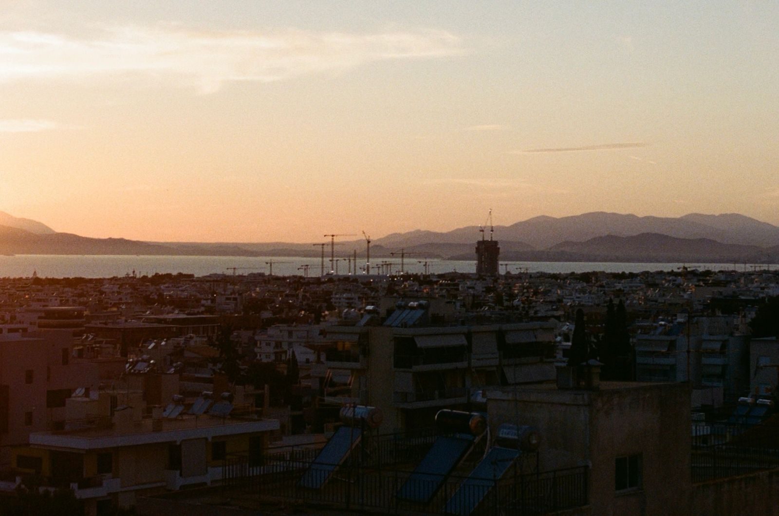 A classic view from an Athenian flat, capturing the simultaneous positionality of the sea as something reachable, as well as distant, mediated by complex networks, spheres of privatisation and a heavy redevelopment apparatus. The photograph is taken by the author.