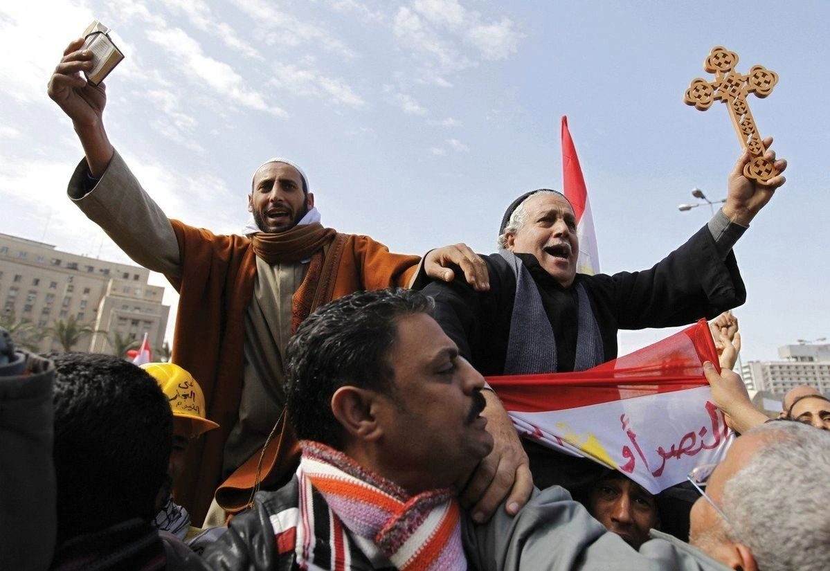 Muslim and Coptic protesters lift Quran and cross in Tahrir Square by Dylan Martinez